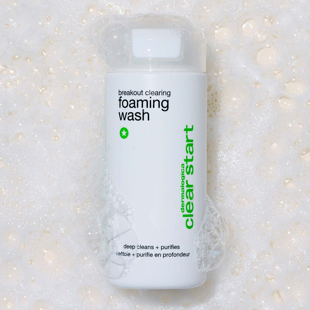 Bottle of breakout clearing foaming wash with visible text on a textured white background