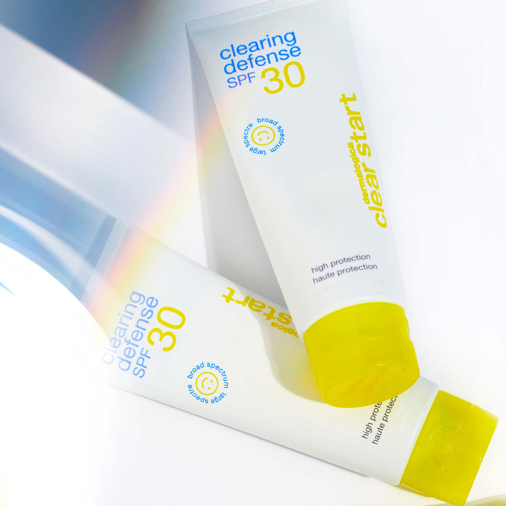 Two tubes of 'Clearing Defense SPF 30' sunscreen with a rainbow effect on a white background.