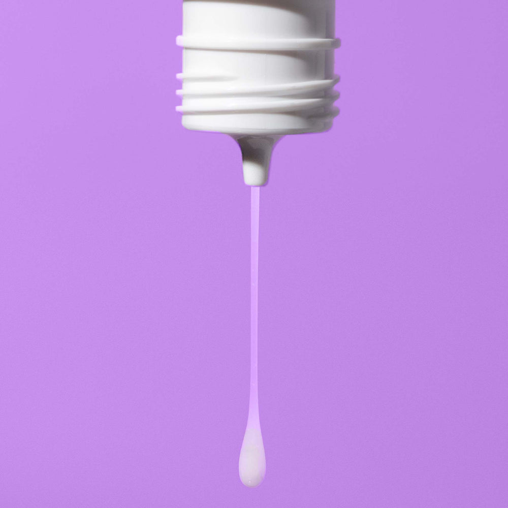 White dropper bottle with a drop of liquid against a purple background