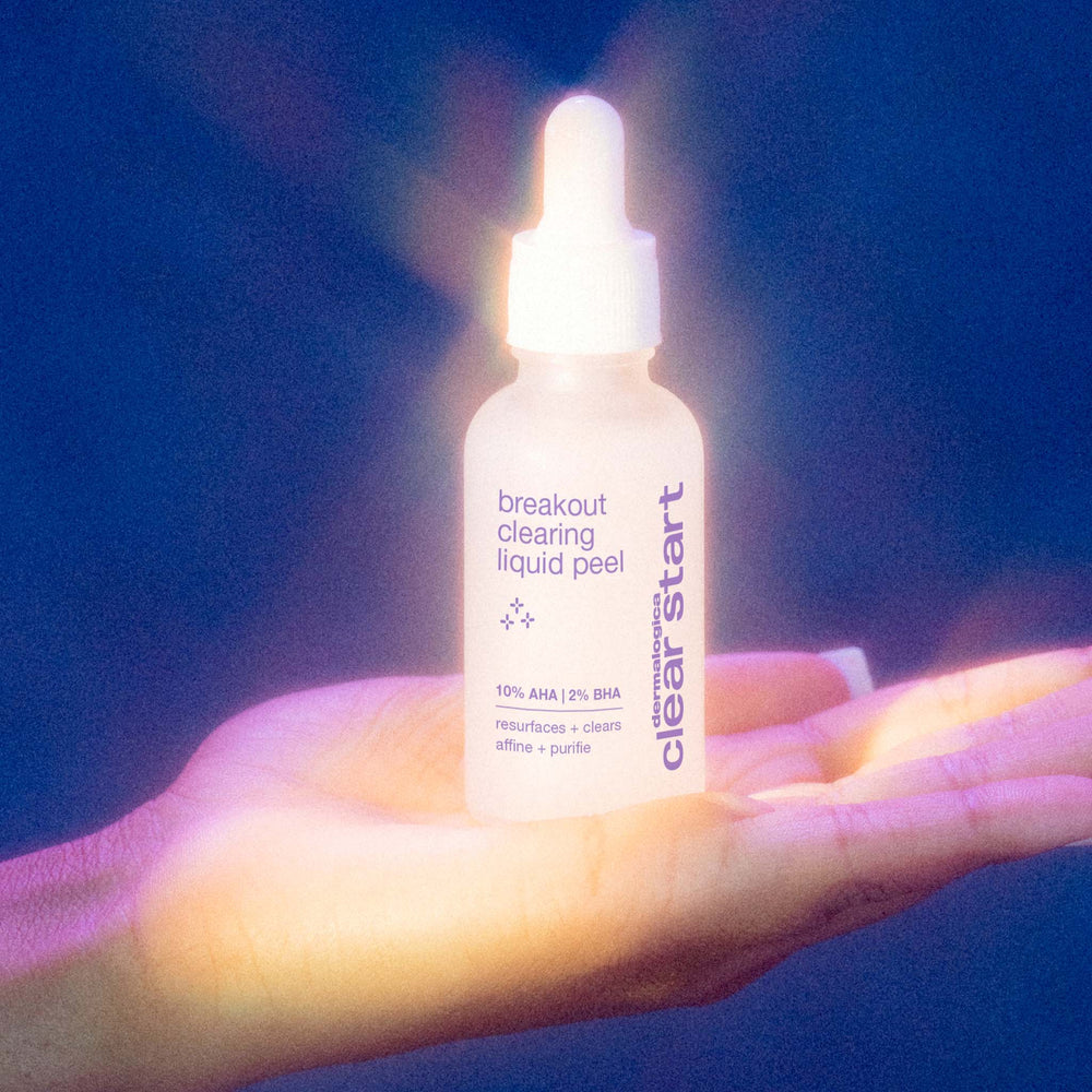 Bottle of 'breakout clearing liquid peel' held in a hand against a dark background