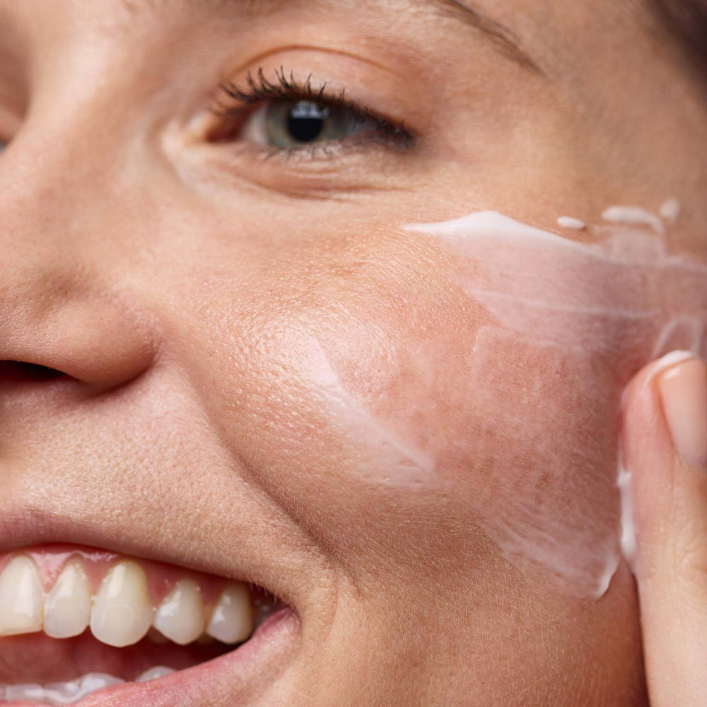 Close-up of a person applying intensive moisture balance cream to their face