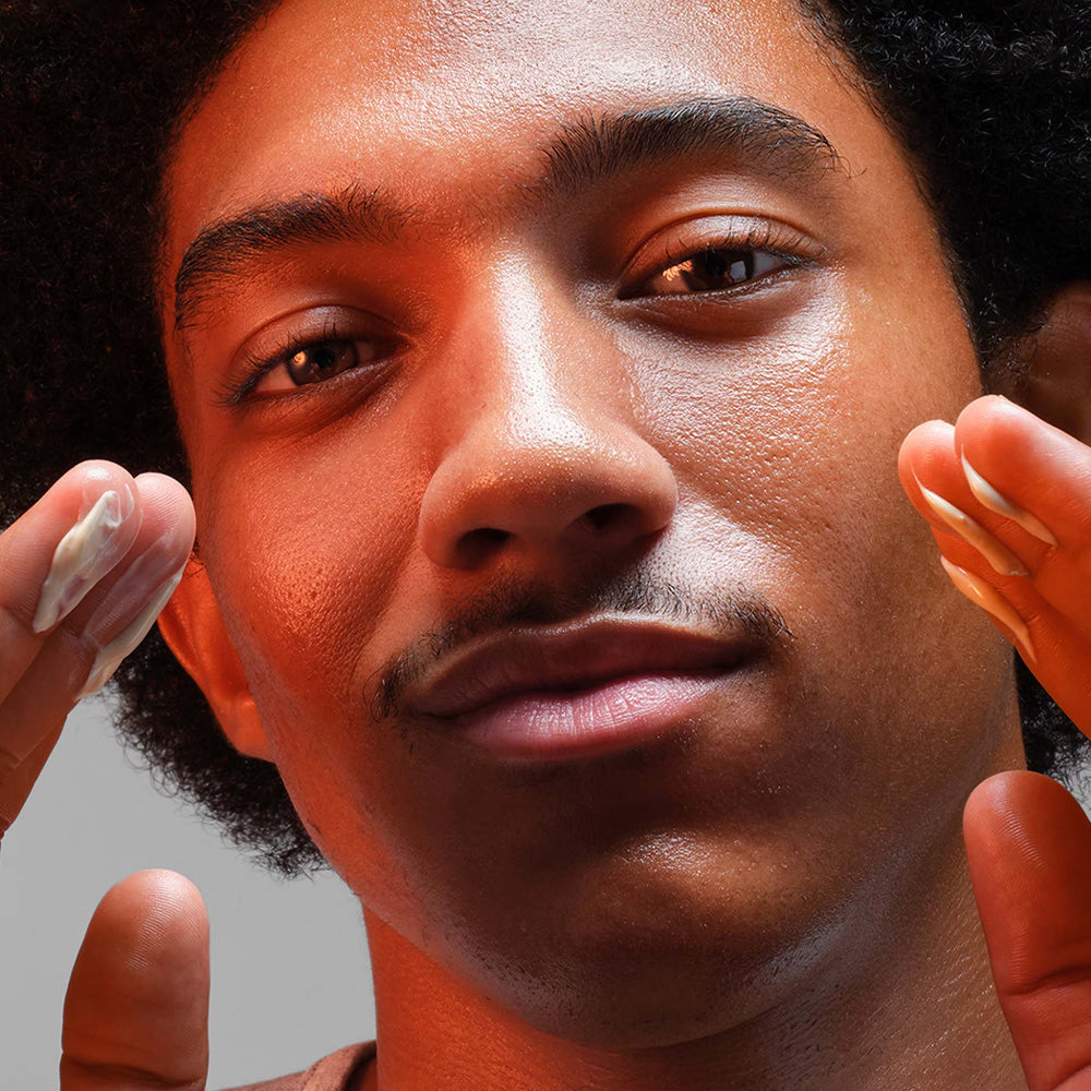 Close-up of a person applying biolumin-c heat aging protector spf15 to their face.