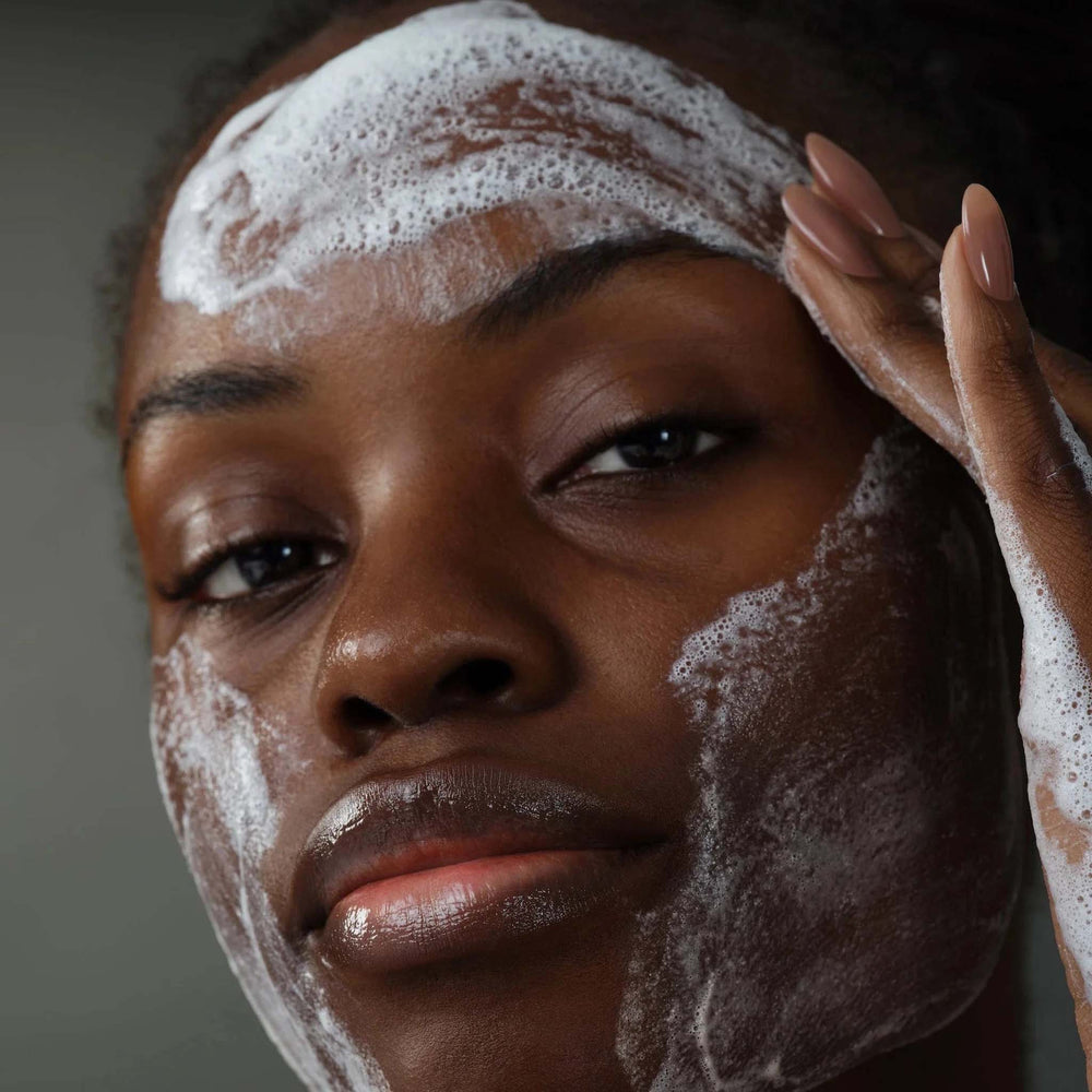 Woman applying dermalogica daily microfoliant with soapy texture to her face.