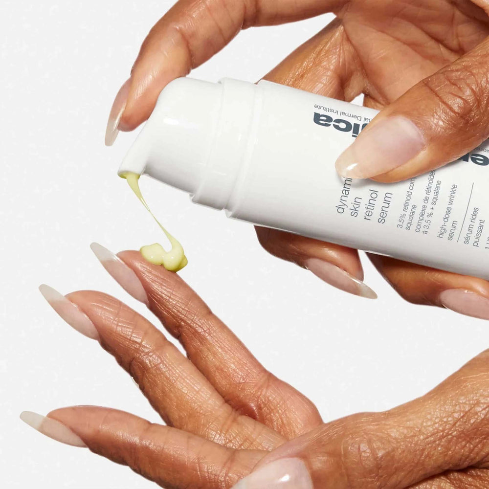 Hand holding a dermalogica dynamic skin retinol serum with visible droplet on a neutral background