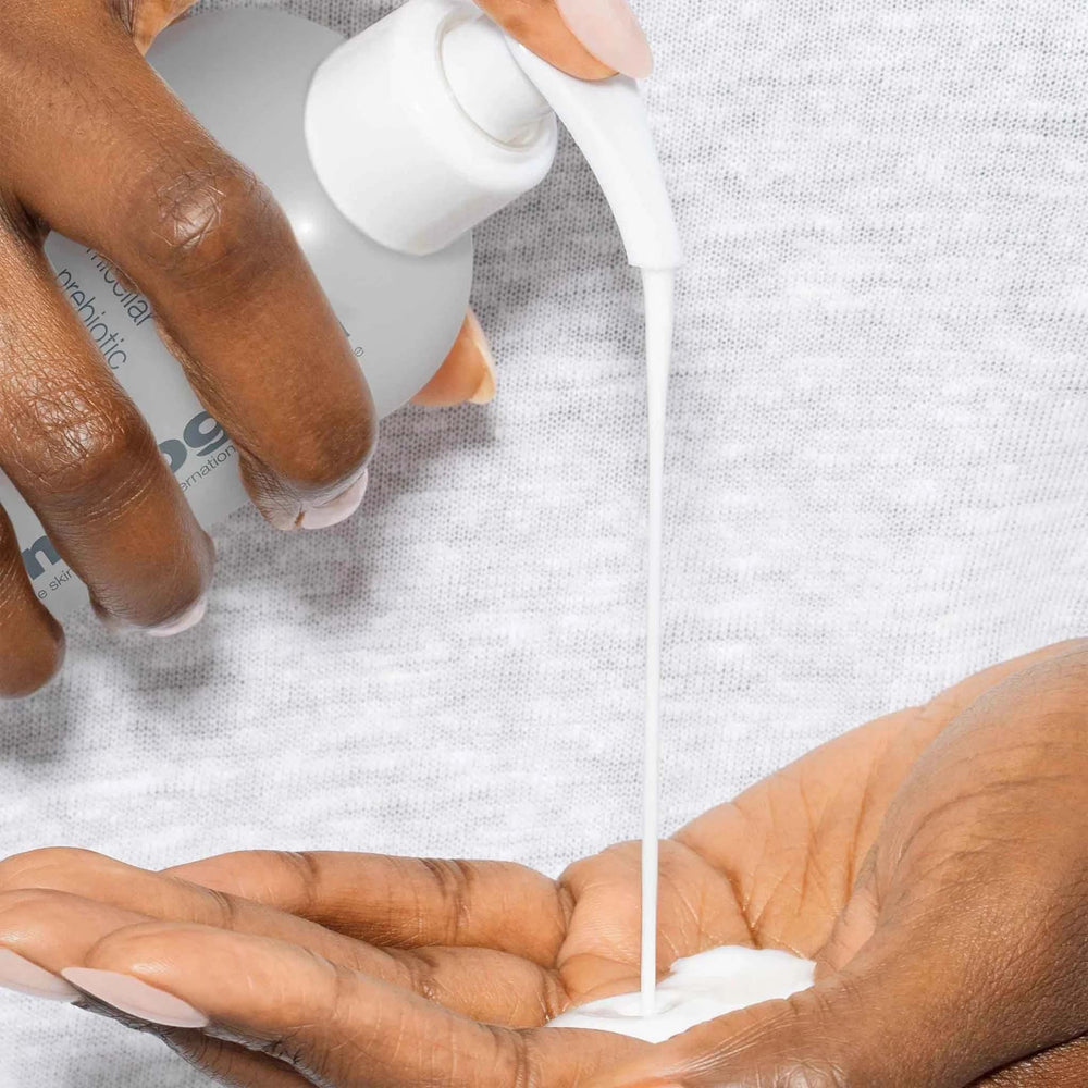 Hand pouring dermalogica micellar prebiotic precleanse onto another hand against a light gray background