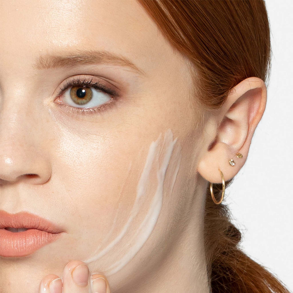 Close-up of a woman's face with a dermalogica micellar prebiotic precleanse  applied to her cheek.