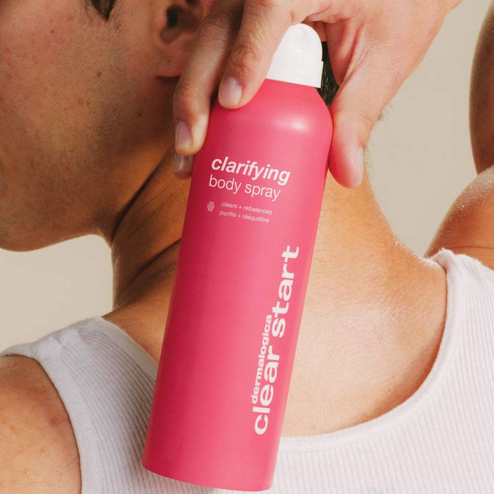 Person using a pink 'Clear Start' clarifying body spray bottle.